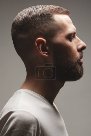 Photo for Male beauty concept. Profile portrait of charismatic active 30-year-old man posing over gray background and meditating. Perfect haircut. Hipster style. Close up. Studio shot - Royalty Free Image