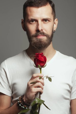 Photo for Male beauty concept. Portrait of romantic charismatic 30-year-old man posing over gray background. with red rose Perfect haircut. Hipster style. Close up. Studio shot - Royalty Free Image