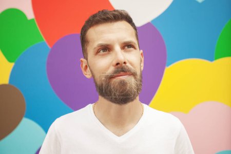 Photo for Love concept. Portrait of proud charismatic active 30-year-old man posing over colourful background. Perfect haircut. Hipster style. Close up. Outdoor shot - Royalty Free Image