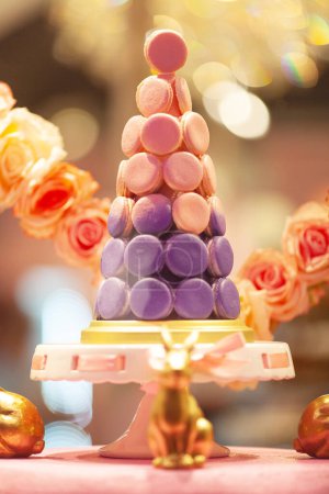 Photo for Pyramid made of french macarons on pedestal cake plate, decorated with roses. Window of sweet shop. Close up. Indoor shot - Royalty Free Image