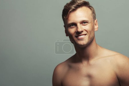 Photo for Male beauty concept. Portrait of smiling 30-year-old sportsman posing over light gray background. Close up. Copy-space. Athlete style. Wavy glossy blond hair. Studio shot - Royalty Free Image