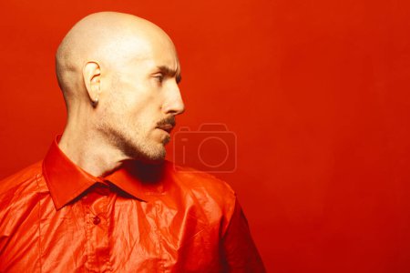Photo for Handsome mature bald 40 years old man in red luxury shirt posing over scarlet background. Profile portrait. Copy-space. Close up. Studio shot - Royalty Free Image