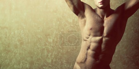 Photo for Roman, Spartan, Greek god concept. Portrait of handsome muscular male model with perfect body posing over golden background with hands up. Healthy clean skin. Banner style. Copy-space. Studio shot - Royalty Free Image