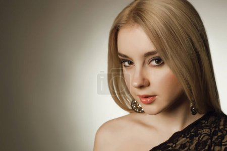 Photo for High class party concept. Portrait of gorgeous young woman with long blond hair posing in black lace cocktail dress over light gray background. Close up. Copy-space. Studio shot - Royalty Free Image