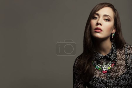 Photo for Luxurious fashionista concept. Portrait of young fashion influencer wearing expensive necklace and earrings posing over gray blackground. Copy-space. Studio shot - Royalty Free Image