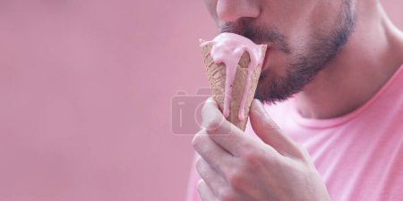 Photo for Pink color obsession concept. Close-up fashion portrait of young man eating melting ice cream over magenta background. Copy-space. Outdoor shot - Royalty Free Image