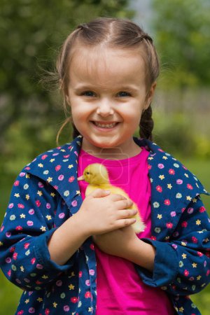 Téléchargez les photos : Jolie petite fille heureuse avec de petits canards dans le jardin. Petite fille tenant un canard dans ses mains. - en image libre de droit