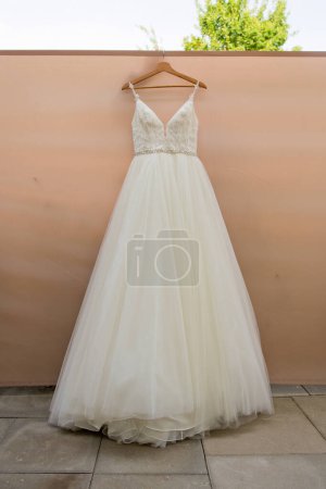 Téléchargez les photos : La délicate robe de mariée est suspendue dans la chambre. Concentration sélective. - en image libre de droit