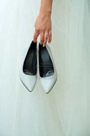 Téléchargez les photos : La mariée tient des chaussures de mariage dans ses mains. - en image libre de droit