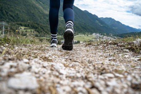 Foto de Vista de primer plano en ángulo bajo de las piernas femeninas en zapatos de senderismo caminando por un sendero en hermosas montañas. - Imagen libre de derechos