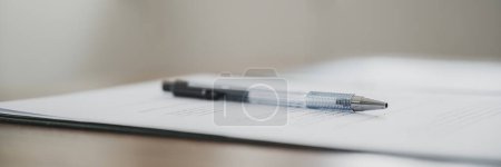 Foto de Vista de bajo ángulo de un bolígrafo negro acostado en un papeleo, contrato o documentos legales. Amplia imagen de vista. - Imagen libre de derechos