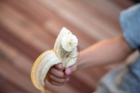 Foto de Vista desde arriba de un niño sosteniendo un plátano medio comido en manos hia. - Imagen libre de derechos