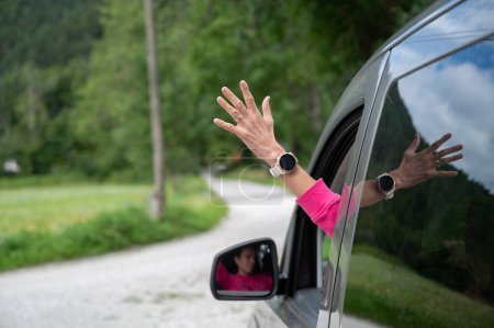 Foto de Mano femenina que sobresale por una ventana de un vehículo de conducción, un coche, en un camino de tierra. - Imagen libre de derechos