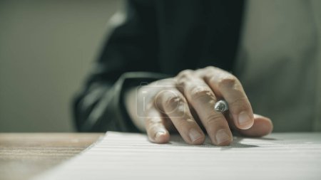 Foto de Vista de bajo ángulo de la mano de un hombre de negocios sosteniendo un bolígrafo mientras lee un informe de contrato o documento. - Imagen libre de derechos