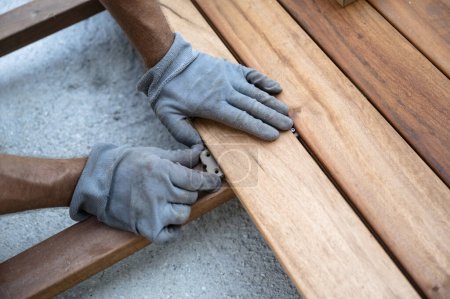Foto de Manos en guantes protectores colocando tablón de madera para suelos de terraza exterior. - Imagen libre de derechos