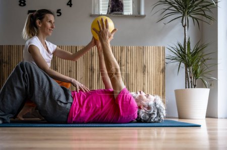 Foto de Fmale fisioterapeuta que trabaja en pilates y ejercicios de postura con un hombre mayor para una salud y la jubilación en forma. - Imagen libre de derechos