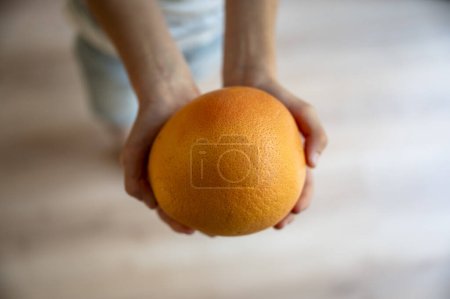 Foto de Vista superior de las manos de un niño sosteniendo una naranja madura o pomelo. - Imagen libre de derechos