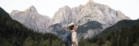 Foto de Vista del perfil de una joven excursionista que mira una hermosa vista de las altas montañas. Amplia imagen de vista. - Imagen libre de derechos