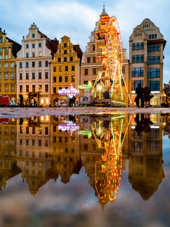 Téléchargez les photos : Wroclaw, Poland - January 2022: Colorful glowing Merry-go-round at center of market square reflected in puddle - en image libre de droit