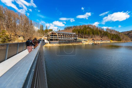 Foto de Zagorze Slaskie, Poland - April 2022: Beautiful landscape of Bystrzyckie lake and hills around seen from small footbridge over lake - Imagen libre de derechos