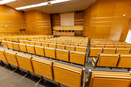 Téléchargez les photos : Wroclaw, Poland - May 2022: Interior of big conference hall of Wroclaw University of Science and Technology full of gray folding chairs and wooden walls - en image libre de droit