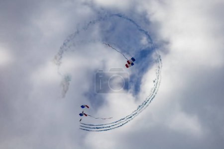 Photo for Leszno, Poland - June 16 2023: Antidotum Airshow Leszno 2023 and show of PHENIX Ambassadeurs Parachutistes flying down on parachutes with french and polish flag and a lot of smoke - Royalty Free Image