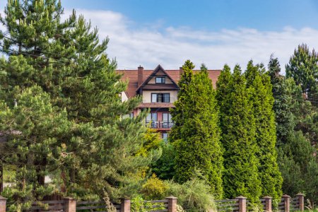 Téléchargez les photos : Smardzewice, Pologne - 9 juin 2023 : Belle façade ancienne de l'hôtel Kruk vue de derrière de hauts arbres verts et des buissons au matin ensoleillé - en image libre de droit