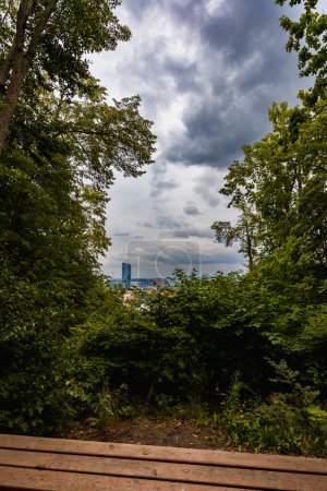 Foto de Gdansk, Polonia - 23 de julio de 2023: Hermoso panorama nublado de la ciudad de Gdansk y rascacielos y edificios corporativos en el distrito de Oliwa visto desde el mirador en la colina Pacholek - Imagen libre de derechos