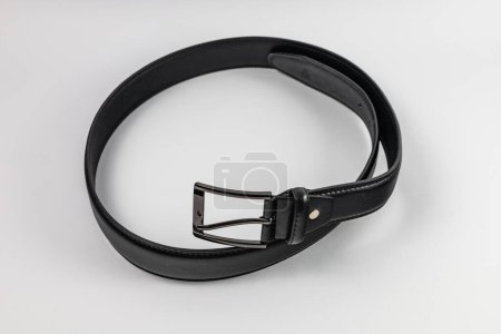 Foto de Cinturón largo y ancho de cuero negro con pocos agujeros pequeños y hebilla grande metálica - Imagen libre de derechos