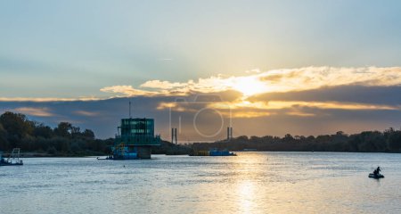 Foto de Varsovia, Polonia - 15 de octubre de 2023: Hermoso amanecer nublado con nubes doradas y sol naciente sobre el largo río Vístula visto desde el bulevar Pinsk Flotilla en la fría mañana - Imagen libre de derechos