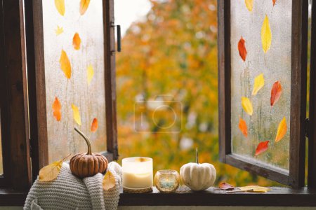 Sweet Home. Still life details in home on a wooden window. Sweater, candle, hot tea and autumn decor. Autumn home decor. Cozy fall mood. Thanksgiving. Halloween. Cozy autumn or winter concept.