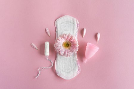 Foto de Concepto de período de menstruación. Almohadilla femenina blanca higiénica, copa menstrual y tampón con flores rosas. Menstruación, protección. Salud de las mujeres - Imagen libre de derechos