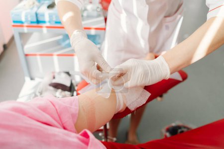 Téléchargez les photos : Une jeune femme qui fait un don de sang à l'hôpital. Une femme fait un don de sang tout en tenant un cœur rouge. Don de sang. - en image libre de droit