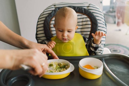 Petit enfant avec une nutrition solide. Bébé fille manger de la nourriture doigt et mélanger assiette de légumes. bébé conduit sevrage BLW auto alimentation.