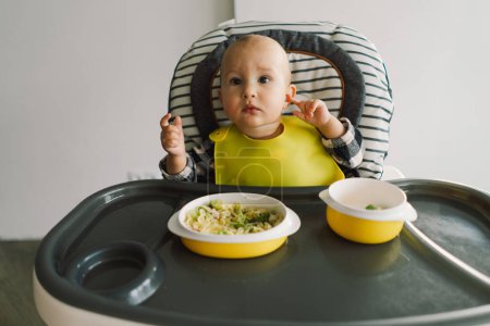 Téléchargez les photos : Petit enfant avec une nutrition solide. Bébé fille manger de la nourriture doigt et mélanger assiette de légumes. bébé conduit sevrage BLW auto alimentation. - en image libre de droit