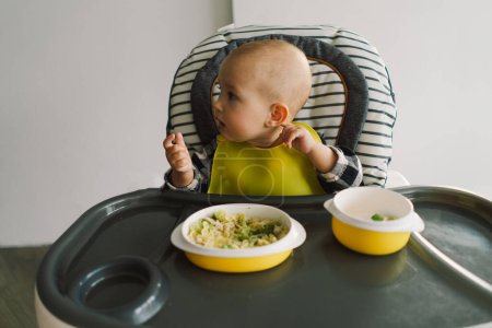 Téléchargez les photos : Petit enfant avec une nutrition solide. Bébé fille manger de la nourriture doigt et mélanger assiette de légumes. bébé conduit sevrage BLW auto alimentation. - en image libre de droit