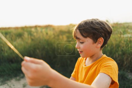 Retratos sinceros. Retrato de un niño en la naturaleza. Un chico con una camiseta naranja vuela una cometa en la naturaleza. Niño feliz, estilo de vida.