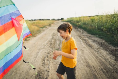 Ehrliche Porträts. Porträt eines Jungen in der Natur. Ein Junge in einem orangefarbenen T-Shirt fliegt einen Drachen in der Natur. Glückliches Kind, Lebensstil.