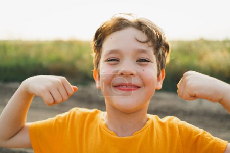 Candid Portraits. Portrait of a boy in nature. portrait of a smiling little brunette boy in an orange T-shirt playing outdoors. happy child, lifestyle.