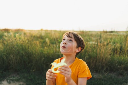 Ehrliche Porträts. Porträt eines Jungen in der Natur. Ein Junge in einem orangefarbenen T-Shirt fliegt einen Drachen in der Natur. Glückliches Kind, Lebensstil.