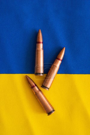 Several bullet casings are neatly arranged on the blue-yellow flag of Ukraine. War in Ukraine. The concept of arms assistance to Ukraine