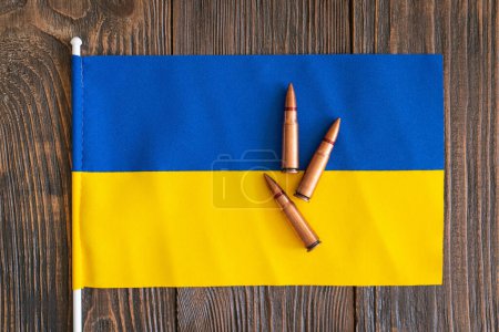 Several bullet casings are neatly arranged on the blue-yellow flag of Ukraine. War in Ukraine. The concept of arms assistance to Ukraine