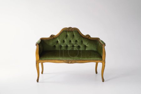 Téléchargez les photos : Un canapé antique exquis tapissé de velours vert peluche se tient gracieusement. Le dossier capitonné et les lignes courbes soulignent l'artisanat d'une époque révolue - en image libre de droit