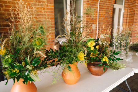 Élégantes pièces maîtresses de fleurs sauvages ornant une table festive à un événement intérieur d'une longue table