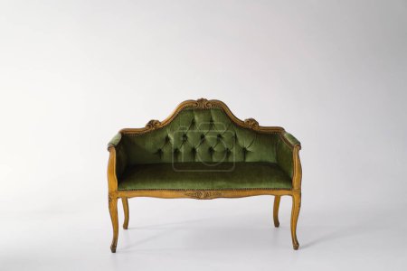 Foto de Un exquisito sofá antiguo tapizado en terciopelo verde felpa se levanta con gracia. El respaldo copetudo y las líneas curvas resaltan la artesanía de una época pasada - Imagen libre de derechos