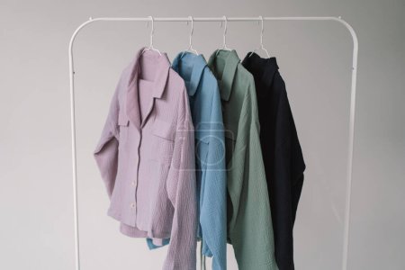 Auf einem Kleiderständer aus Metall ist eine Kollektion bunter Kleidung in verschiedenen Farbtönen von hellrosa bis dunkelblau ausgestellt..