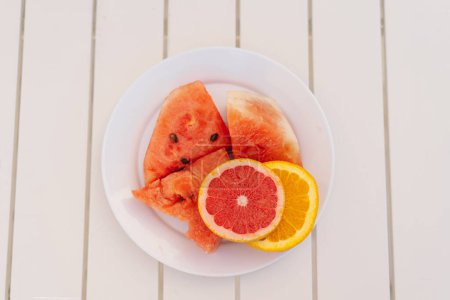 Sliced Watermelon and Citrus Fruits on a White Plate During a Sunny Day