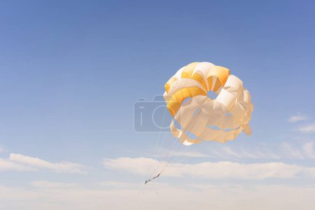 The parachute is fully inflated, showcasing vivid yellow and white colors as it glides through the air.