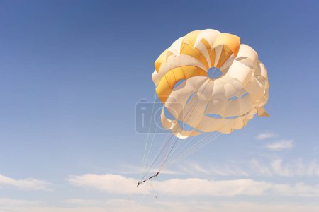Téléchargez les photos : Le parachute est entièrement gonflé, présentant des couleurs jaune vif et blanc pendant qu'il glisse dans les airs. - en image libre de droit