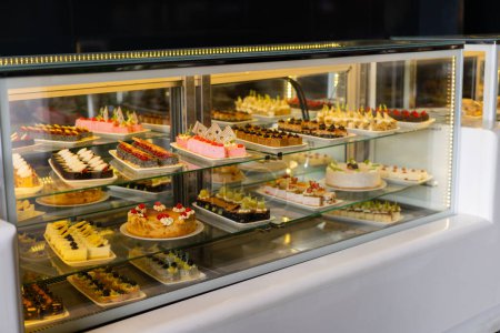 Vitrine avec des bonbons, Divers desserts et gâteaux à vendre dans la pâtisserie. Présentoir en verre au magasin boulangerie pâtisserie.